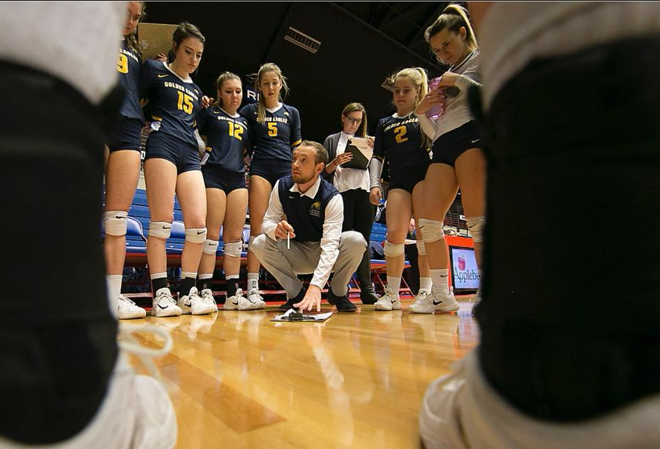 Coach Austin Albers talking to LCCC Volleyball players in a hundle down on the court.