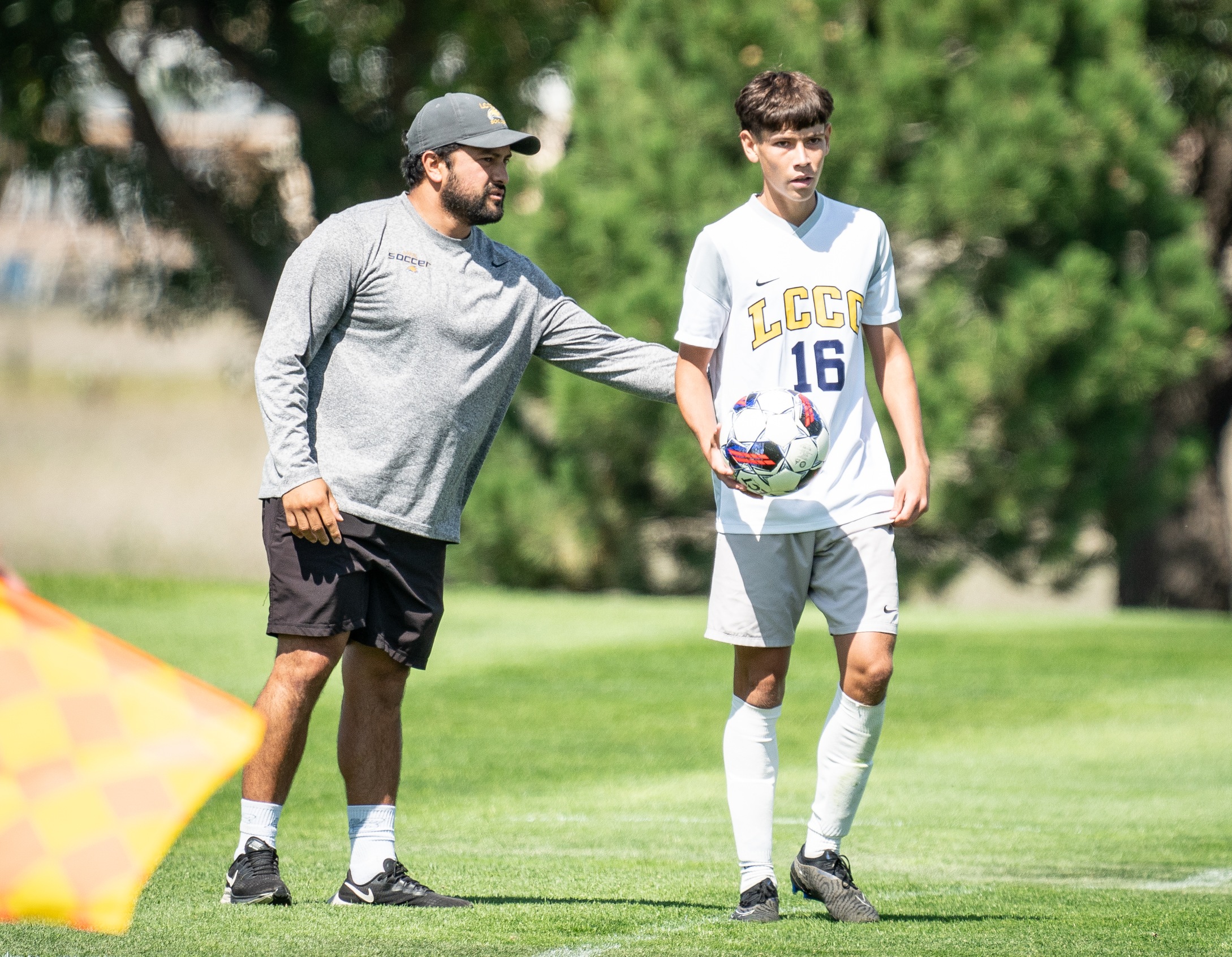 Coach of LCCC talks to player from the sideline as he is about to throw the ball in. 