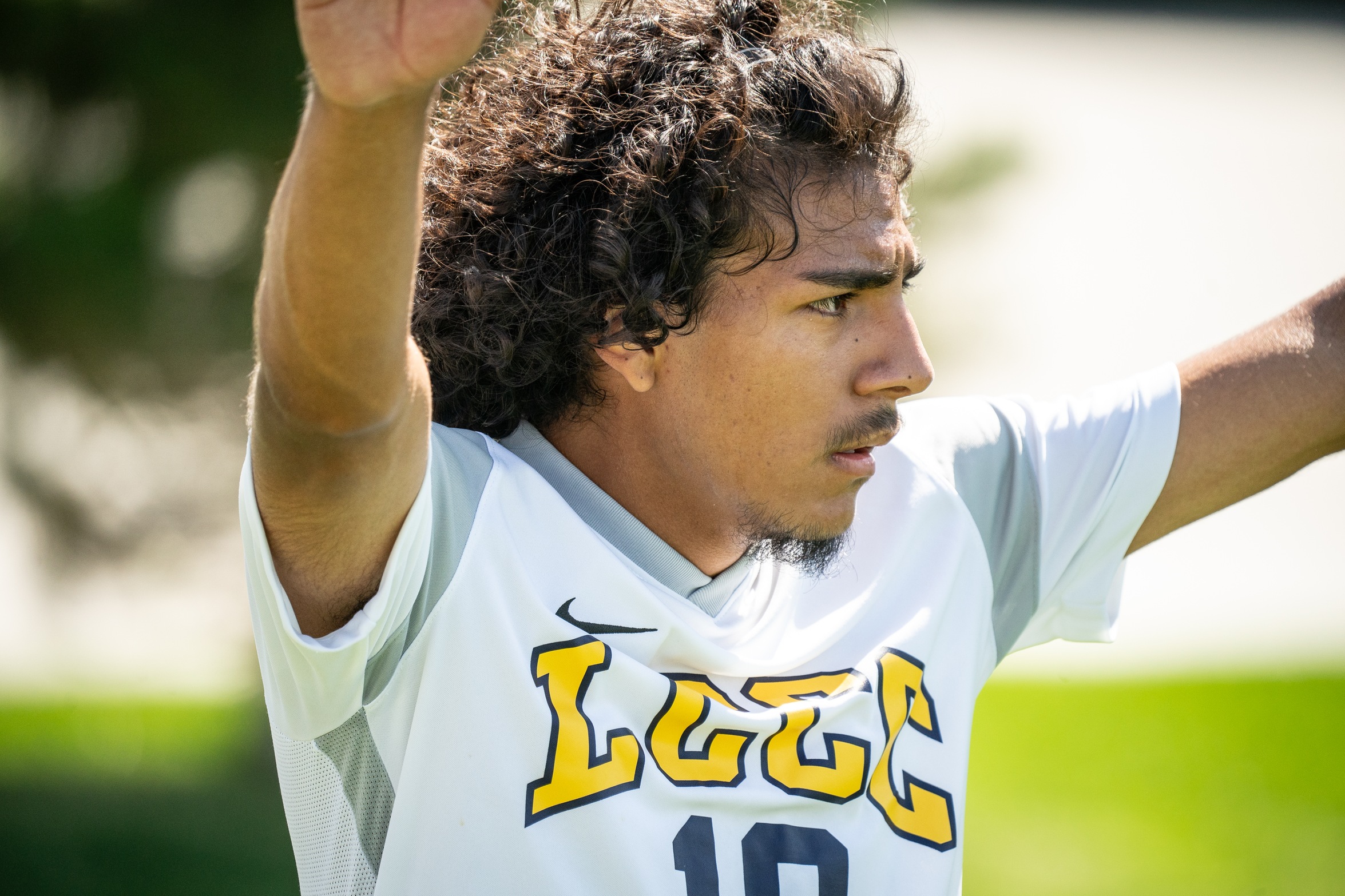 LCCC Player hands raised as he's focused on kicking the corner kick. 